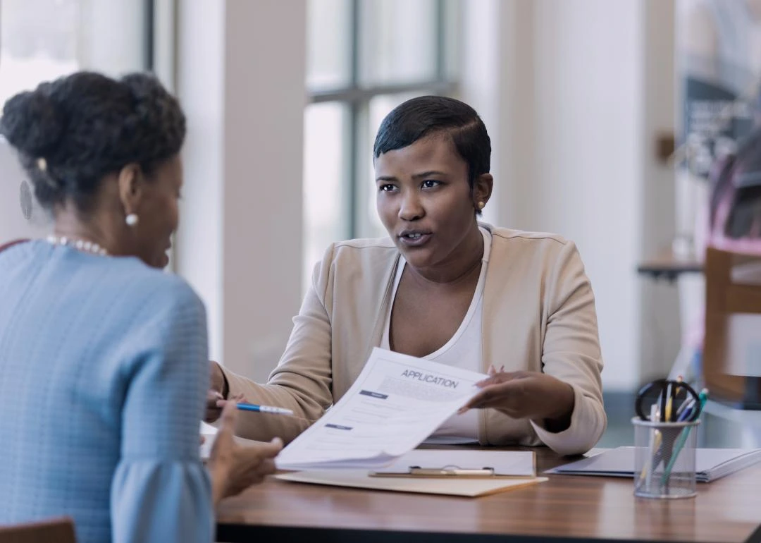 A professional consultation in progress where two individuals are discussing a document labeled "APPLICATION," for a small business financing meeting.